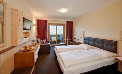 a hotel room with a large bed and a television at Hotel Schennerhof in Schenna