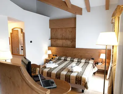 a bedroom with a bed and a laptop on a table at Hotel Al Parco in Moena