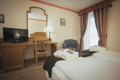 a hotel room with a bed and a desk and a mirror at Hotel Al Parco in Moena