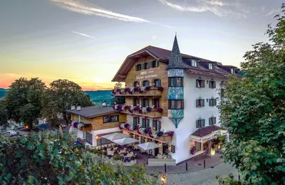 a hotel in the mountains with a building at Hotel Enzian in Siusi