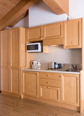 a kitchen with wooden cabinets and a microwave at Residence Civetta in Val di Zoldo