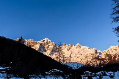 a snow covered mountain with houses in front of it at Residence Civetta in Val di Zoldo