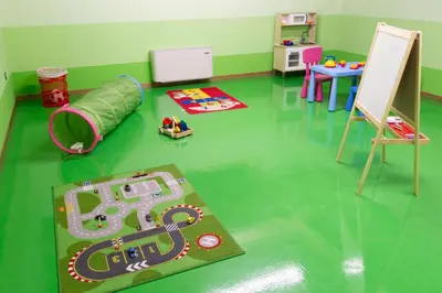 a room with a green floor with a play area at Residence Civetta in Val di Zoldo