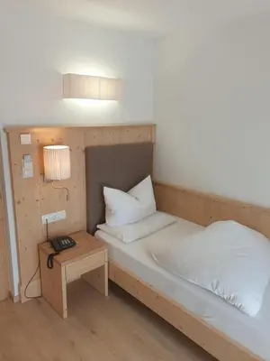 a bedroom with a bed with a lamp and a table at Hotel Rose in Villabassa