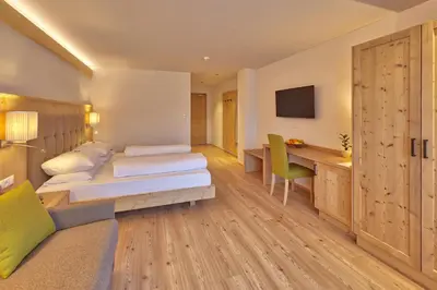 a hotel room with two beds and a desk at Hotel Rose in Villabassa