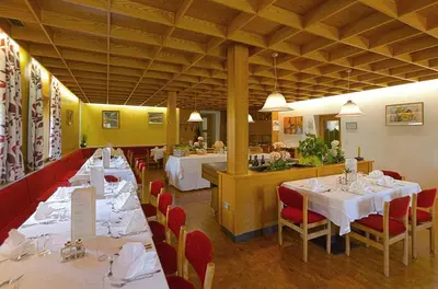 a dining room with tables and red chairs and a restaurant at Hotel Rose in Villabassa