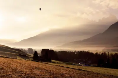 a person flying a kite in a field with mountains at Hotel Rose in Villabassa