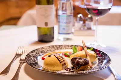 a plate of food on a table with a glass of wine at Hotel Rose in Villabassa
