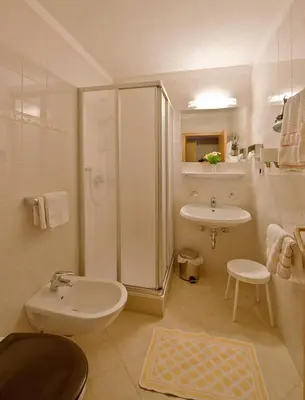 a white bathroom with a shower and a sink at Hotel Rainegg in Valdaora