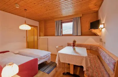 a room with two beds and a table and a window at Hotel Rainegg in Valdaora