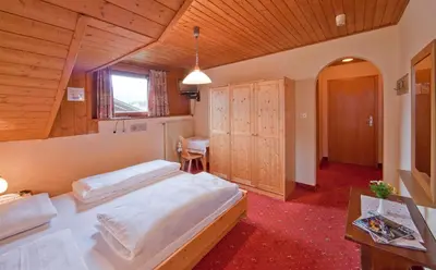 a large bedroom with two beds and a desk at Hotel Rainegg in Valdaora