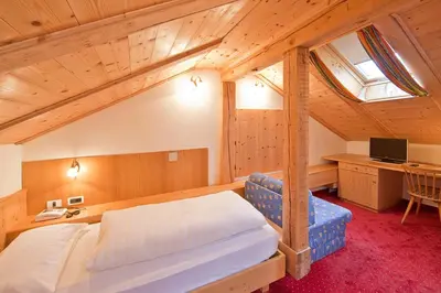 a bedroom with a bed and a desk in a attic at Hotel Rainegg in Valdaora