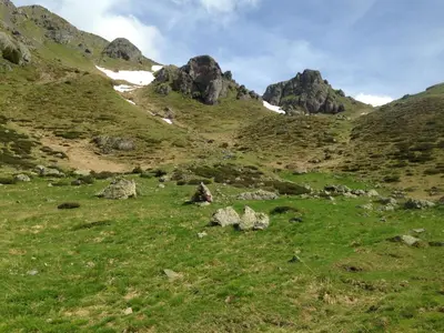 a grassy field with rocks and mountains in the background at il bosco in casa in Telve