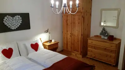 a bedroom with a bed with two hearts on the pillows at il bosco in casa in Telve