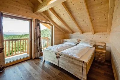 a bed in a wooden room with a large window at Camping Chalet Salten in San Genesio Atesino