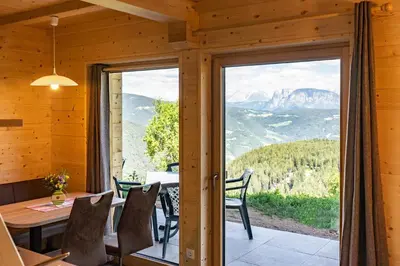 a dining room with a table and chairs and a large window at Camping Chalet Salten in San Genesio Atesino