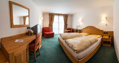 a bedroom with a bed and a desk and a mirror at Il Falchetto in Sarnonico