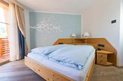 a bedroom with a large bed with a wooden headboard at Il Falchetto in Sarnonico