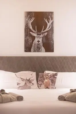 a bed with a picture of a deer and pillows at Hotel Villa Melì in Predazzo
