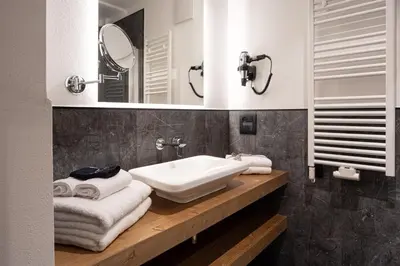 a bathroom with a sink and a mirror and towels at Hotel Villa Melì in Predazzo