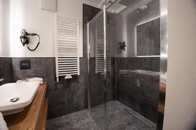a bathroom with a glass shower and a sink at Hotel Villa Melì in Predazzo