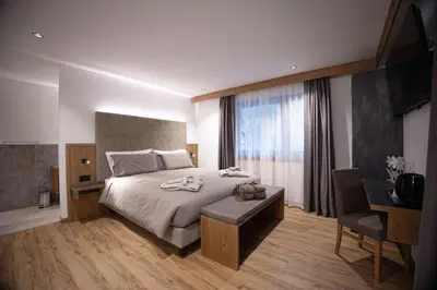 a bedroom with a large bed with a desk and a chair at Hotel Villa Melì in Predazzo