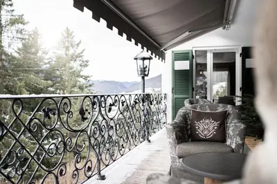 a balcony with a chair and a table on a porch at Alpstay - Chalet Hotel Hartmann - Adults Only in Ortisei