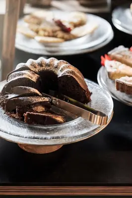 a chocolate bundt cake on a plate with a knife at Alpstay - Chalet Hotel Hartmann - Adults Only in Ortisei