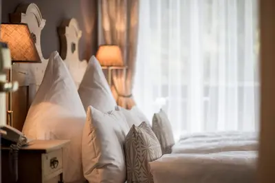 a bedroom with a bed with white pillows and a window at Alpstay - Chalet Hotel Hartmann - Adults Only in Ortisei