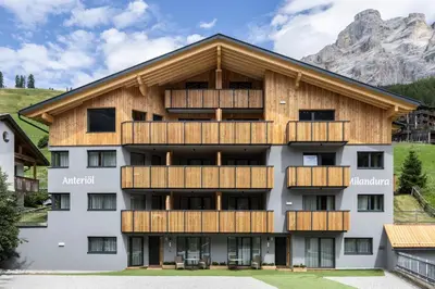 an apartment building with wooden balconies and a mountain at Ciasa Anteriol NEW SUMMER 2025 in San Cassiano