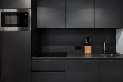 a black kitchen with a sink and a microwave at Ciasa Anteriol NEW SUMMER 2025 in San Cassiano