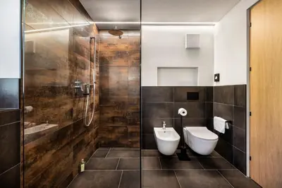 a bathroom with a toilet and a glass shower at Ciasa Anteriol NEW SUMMER 2025 in San Cassiano