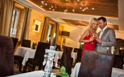 a man and woman drinking wine in a restaurant at Aktiv & Relax Hotel Hubertus in Villandro