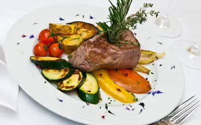 a plate of food with meat and vegetables on a table at Aktiv & Relax Hotel Hubertus in Villandro