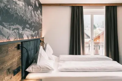 two beds in a hotel room with a window at Kristiania Small Dolomites Hotel in Selva di Val Gardena