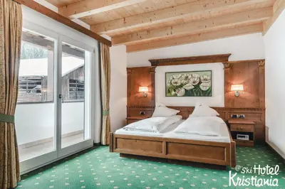 a bedroom with a bed and a large window at Kristiania Small Dolomites Hotel in Selva di Val Gardena