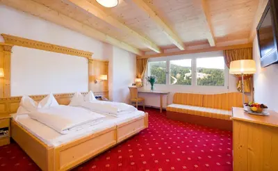 a hotel room with a bed and a couch at Kristiania Small Dolomites Hotel in Selva di Val Gardena