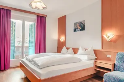 a bedroom with a bed and a chair at Kristiania Small Dolomites Hotel in Selva di Val Gardena