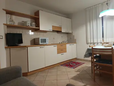 a kitchen with white cabinets and a table with a microwave at Hotel Residence Rosa in San Lugano