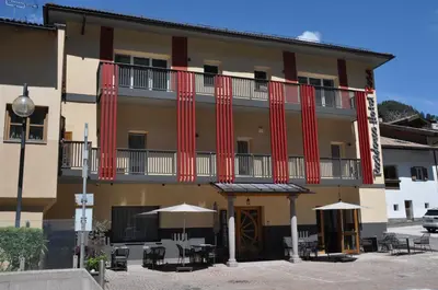 an apartment building with red columns and tables and umbrellas at Hotel Residence Rosa in San Lugano