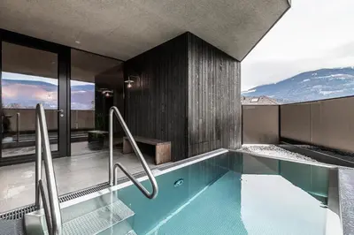 a house with a swimming pool with mountains in the background at Hotel Restaurant Langgenhof in Brunico