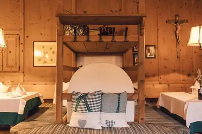 a bed in a room with two tables at Hotel Restaurant Langgenhof in Brunico