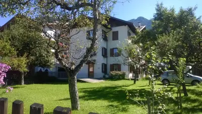 a white house with a car parked in a yard at b&b Casa Tavernaro in Fiera di Primiero