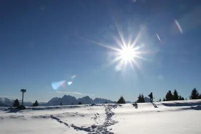 a snow covered field with the sun in the sky at Landhof in Monguelfo