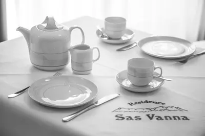 a table with plates and cups and utensils on it at Residence Sas Vanna in La Villa