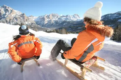 two people sitting on a sled in the snow at Residence Sas Vanna in La Villa