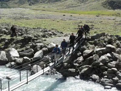 a group of people walking over a bridge over a river at Sporthotel Kalcherhof in Racines