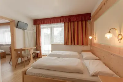 a bedroom with two beds and a table at B&B Apartments La Palsa in San Cassiano