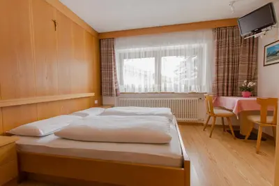 a bedroom with a bed and a table and a window at B&B Apartments La Palsa in San Cassiano