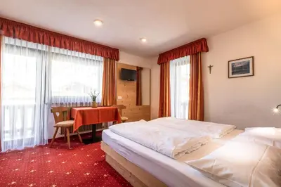 a hotel room with two beds and a table at B&B Apartments La Palsa in San Cassiano